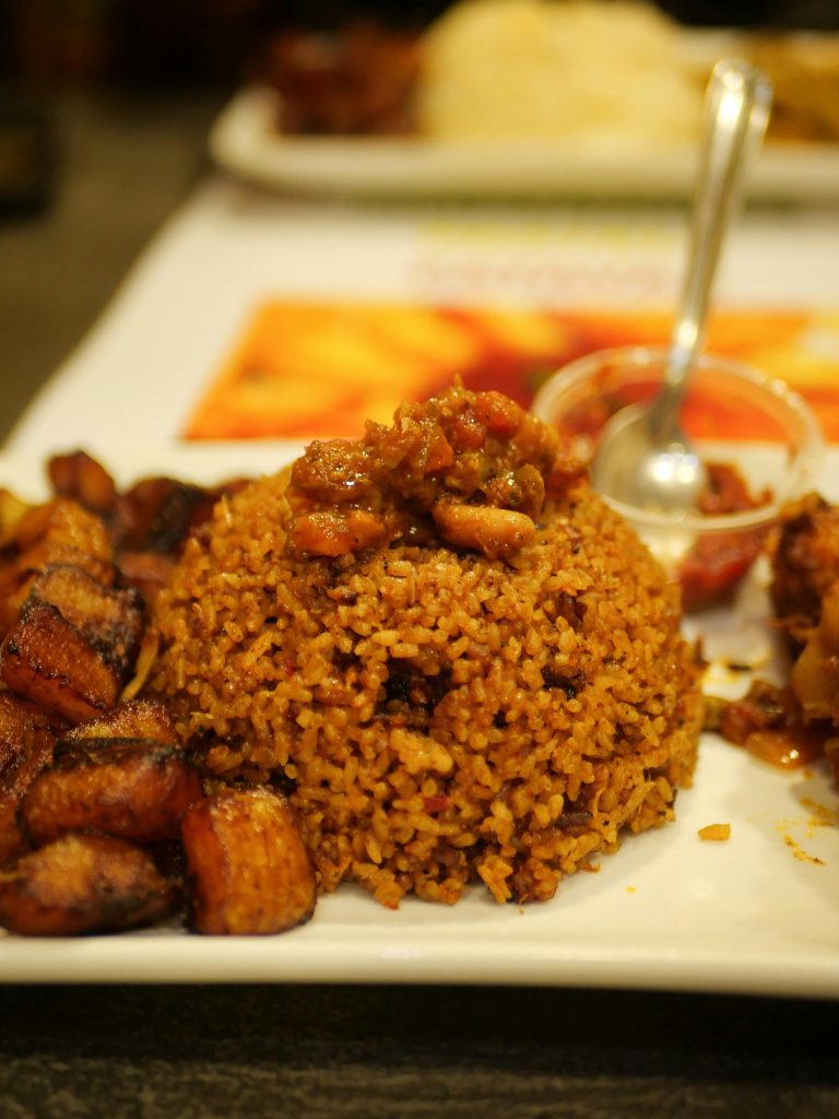 A tempting plate of Jollof rice accompanied by savory fried plantains. Perfect meal idea.